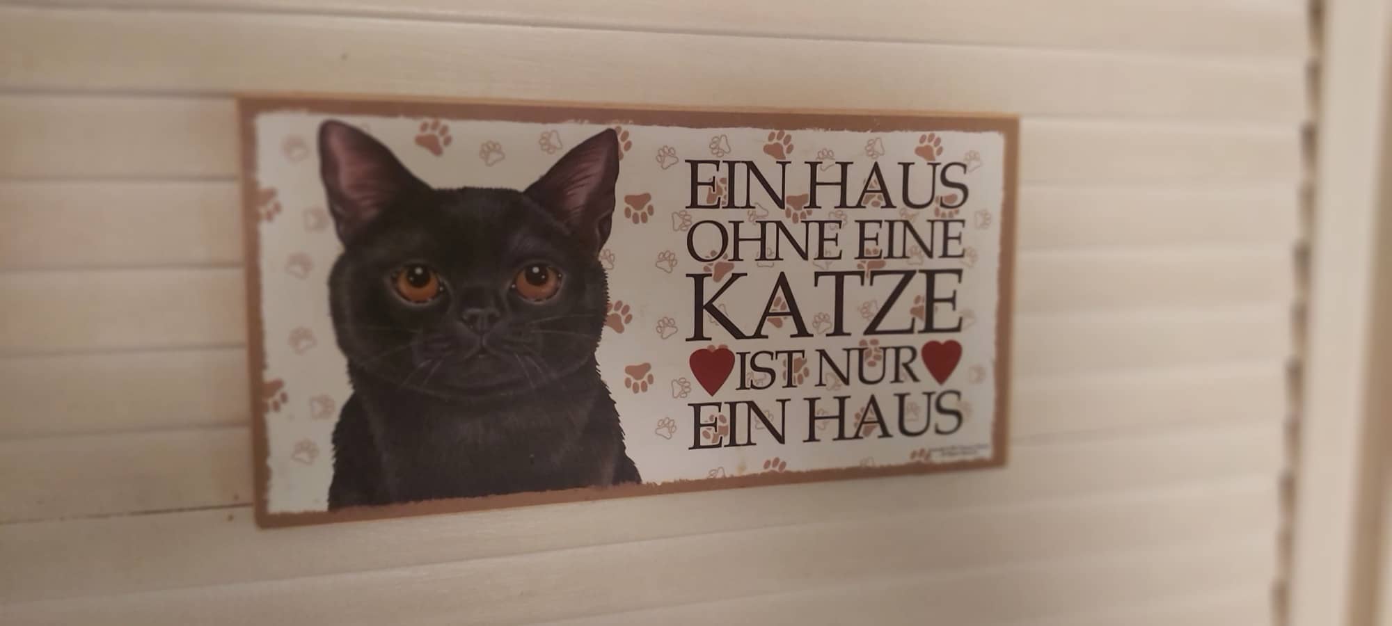 Holzschild mit der Aufschrift „Ein Haus ohne eine Katze ist nur ein Haus“