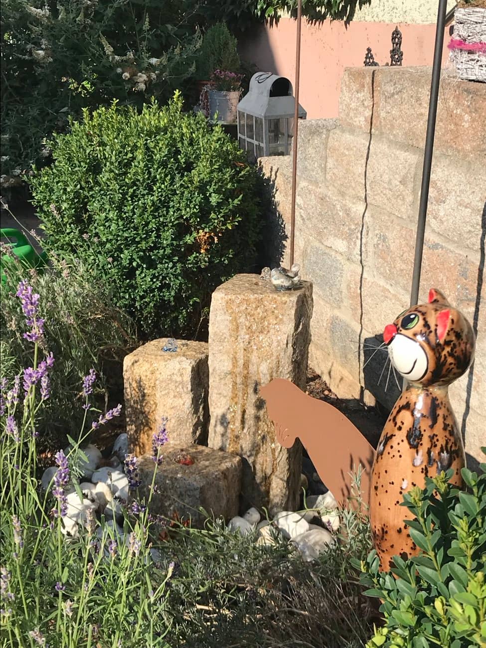 Steingarten mit Wasserlauf, Lavendel und einer bunten Keramik-Katzenfigur